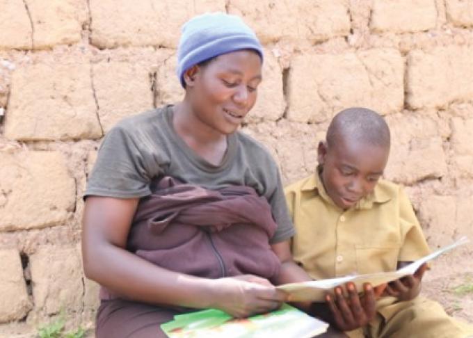 Mfitumukiza and his mother read together a storybook borrowed from the reading club